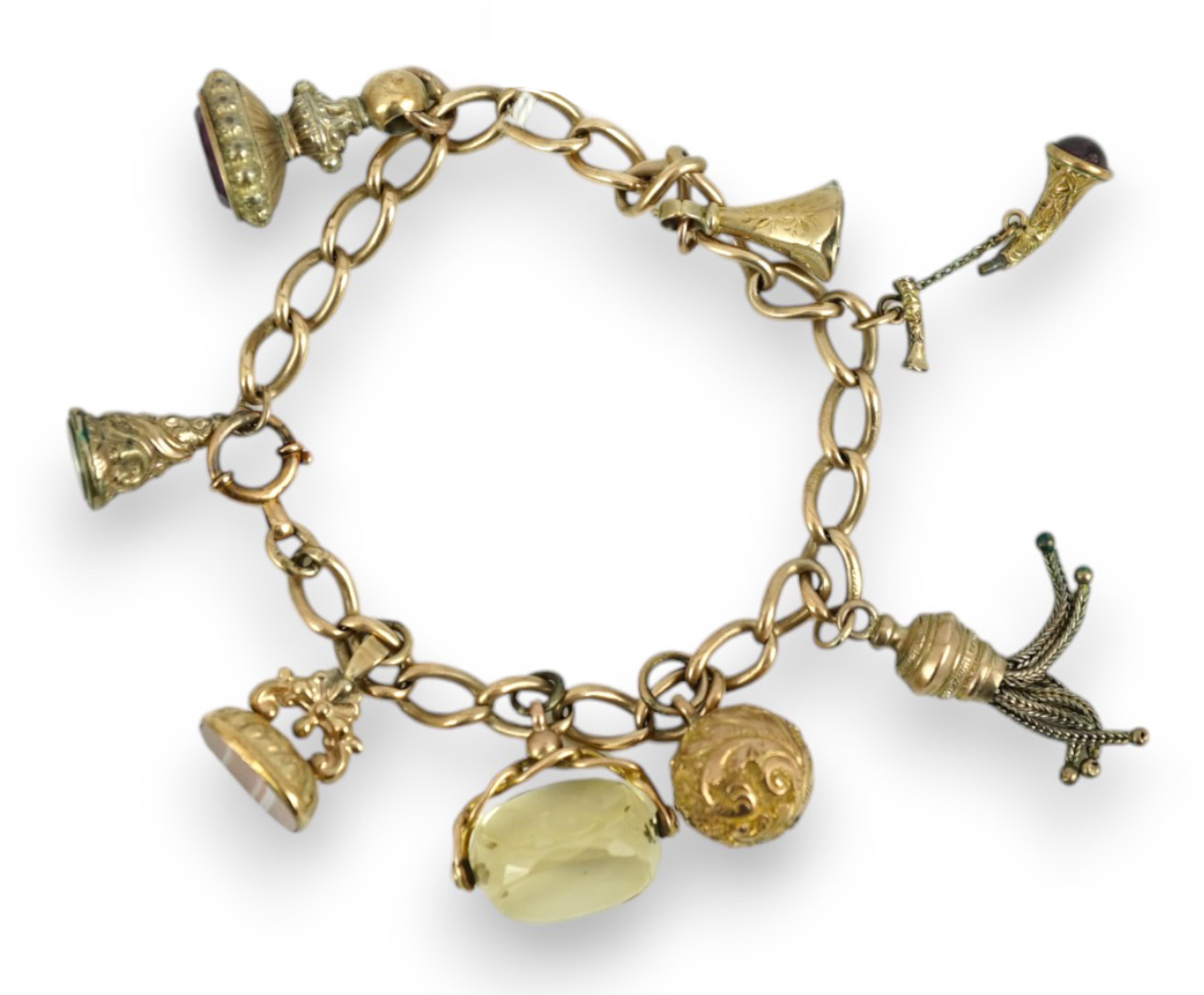 A 9ct gold charm bracelet, hung with eight assorted yellow metal overlaid charms, gross weight 33.4 grams.